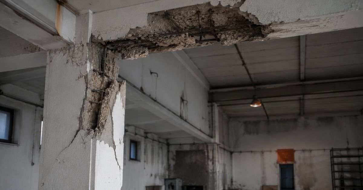 Pilar y forjado de una nave industrial con el hormigón desprendido y la armadura al descubierto